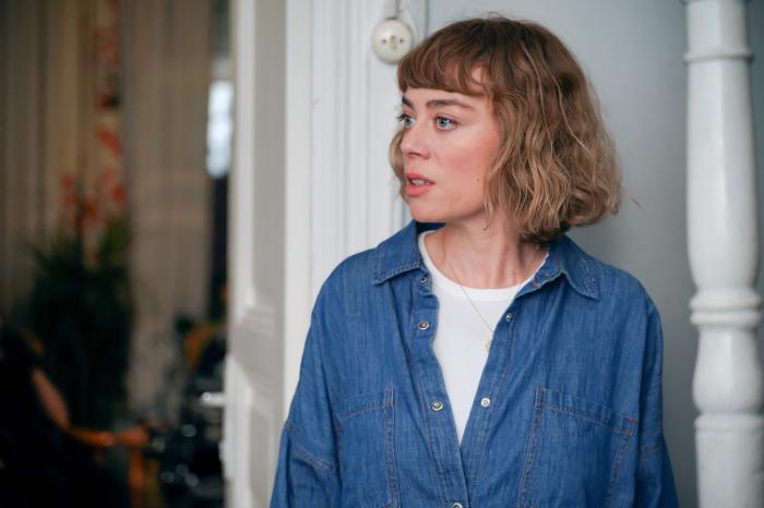 Demet Evgar poartă un tricou alb, o cămașă albastră și are părul scurt