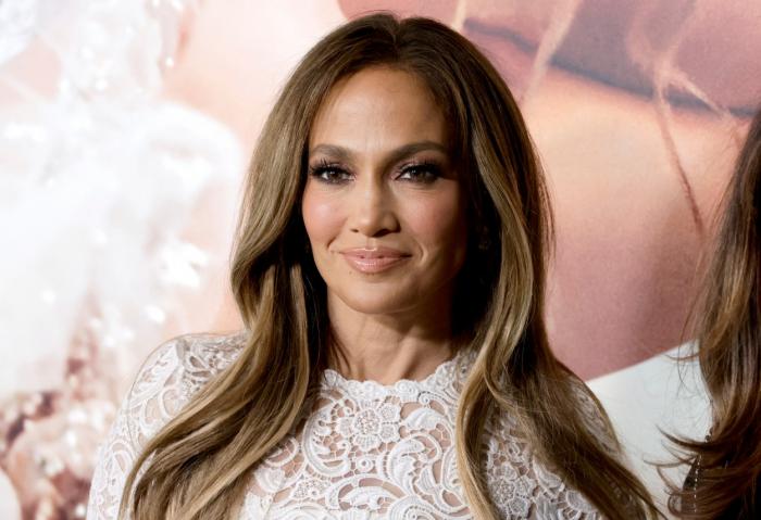 Jennifer Lopez poartă o rochie albă și are părul desprins