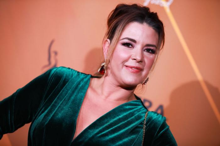 Alicia Machado poartă o rochie de catifea verde și are părul prins în coc