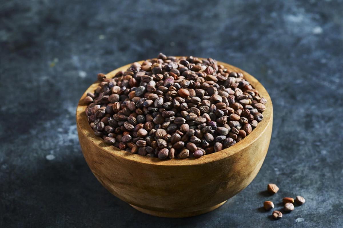 Un bol cu seminte de ridichi așezat pe o masă. Lângă bol se află câteva semințe de ridichi