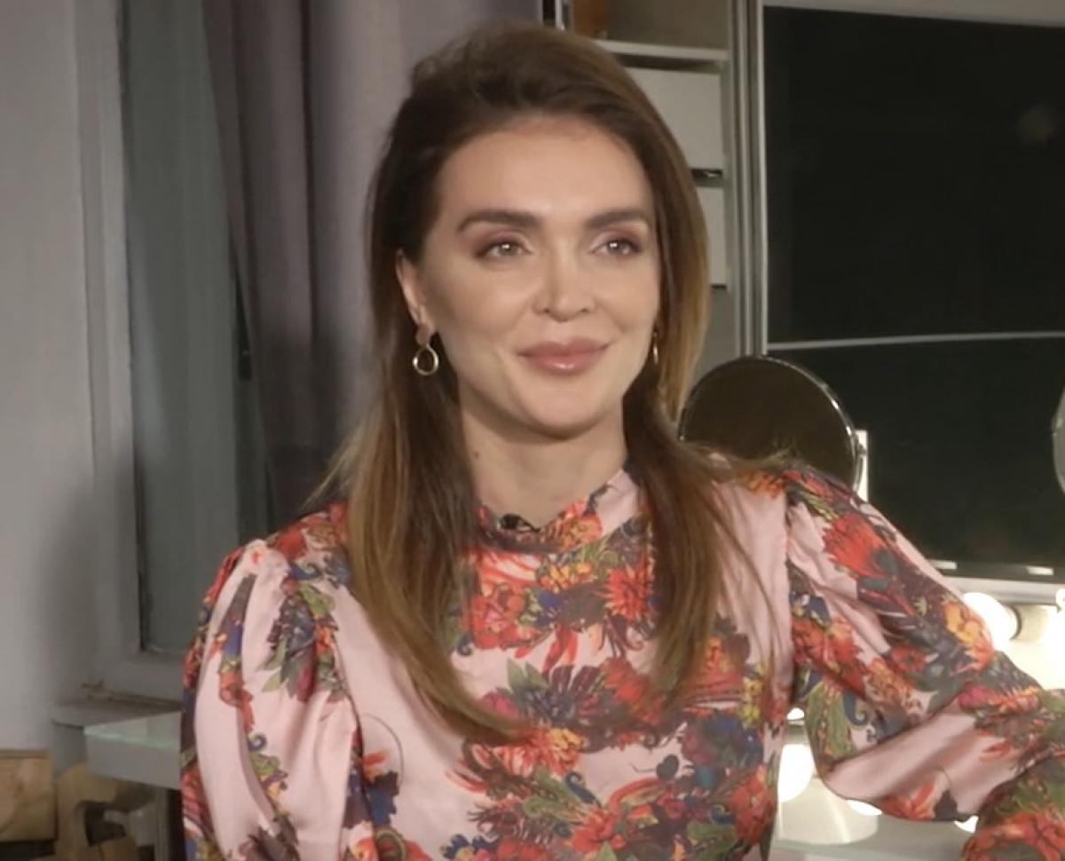 Isabel Strat poartă o rochie cu flori, are un machiaj de seară și zâmbește