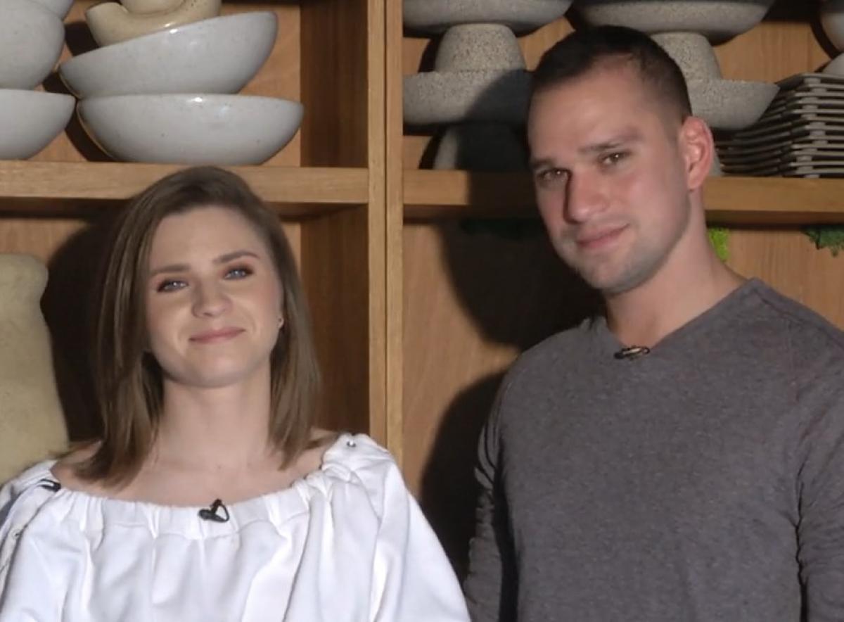 Criss poartă o bluză albă și zâmbește, iar Vlad poartă o bluză închisă la culoare și zâmbește