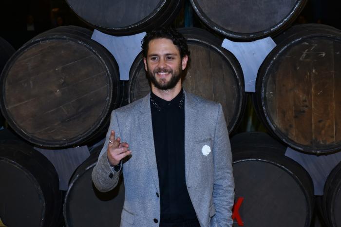 Christopher Uckermann poartă un tricou negru și un costum gri deschis