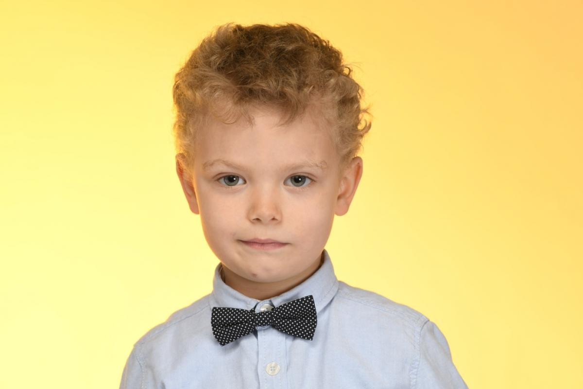 Emre Mete Sönmez poartă o cămașă albastră și papillon. Are părul cârlionțat și un zâmbet discret