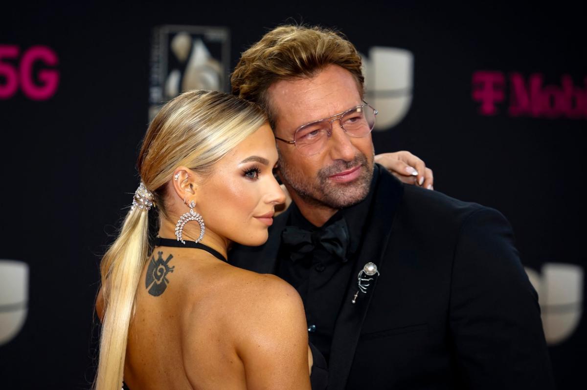 Irina Baeva poartă o rochie cu spatele gol și are părul prins în coadă de cal, iar Gabriel Soto poartă un costum negru și ochelari
