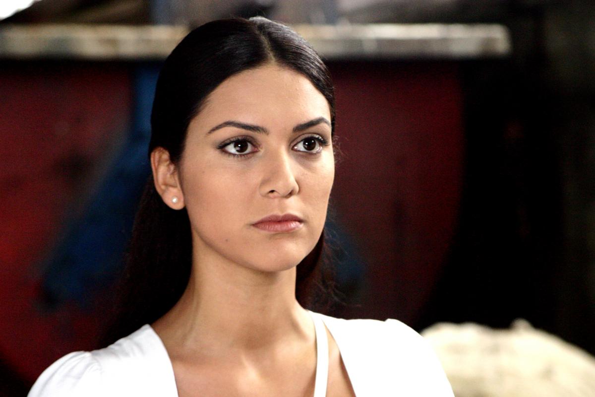 Bergüzar Korel poartă o rochie albă și are părul lung și prins la spate