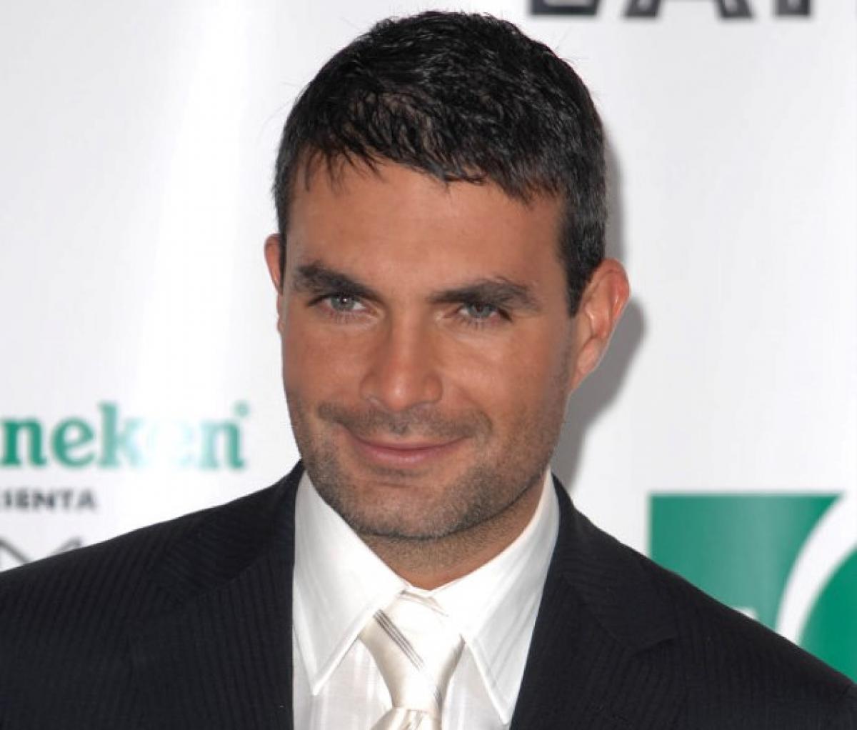 Mauricio Islas poartă costum și zâmbește