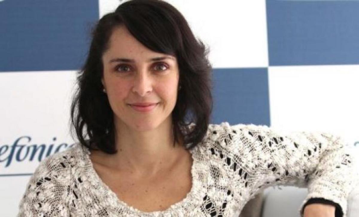 Irán Castillo poartă o bluză albă, zâmbește și are părul despins