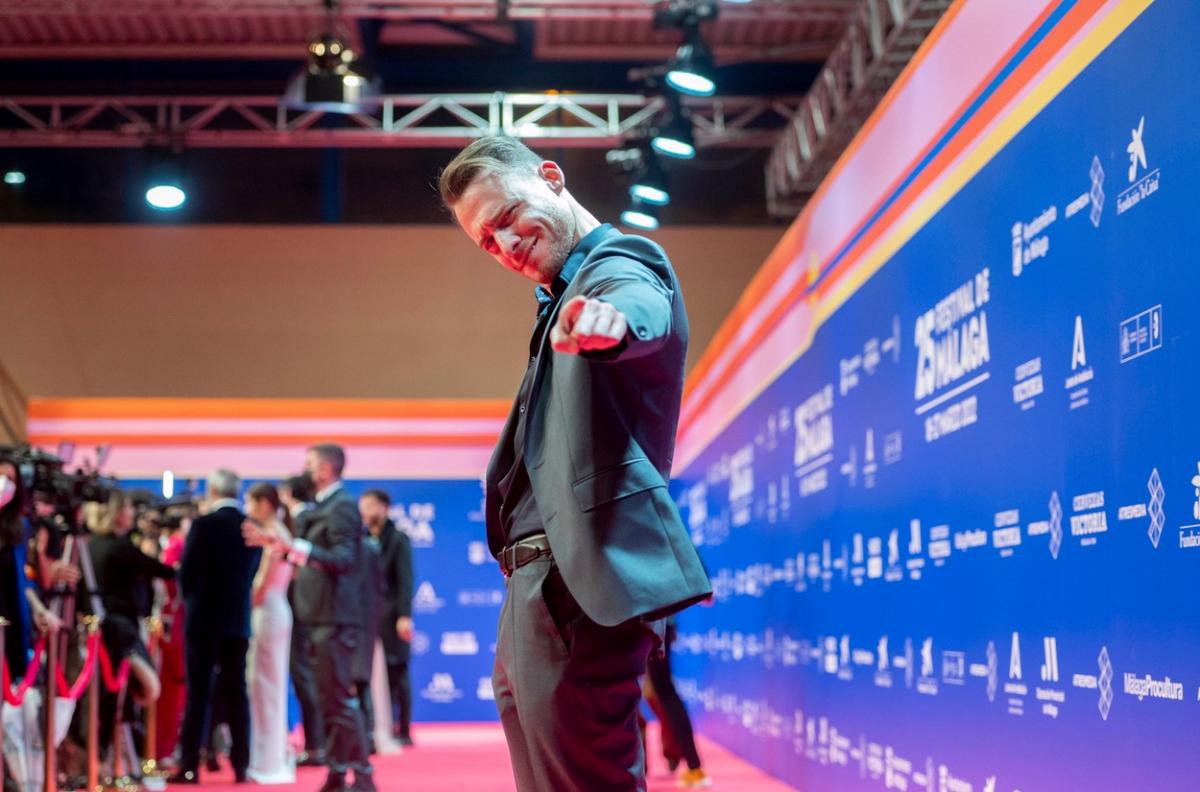 Kerem Bürsin poartă un costum și zâmbește