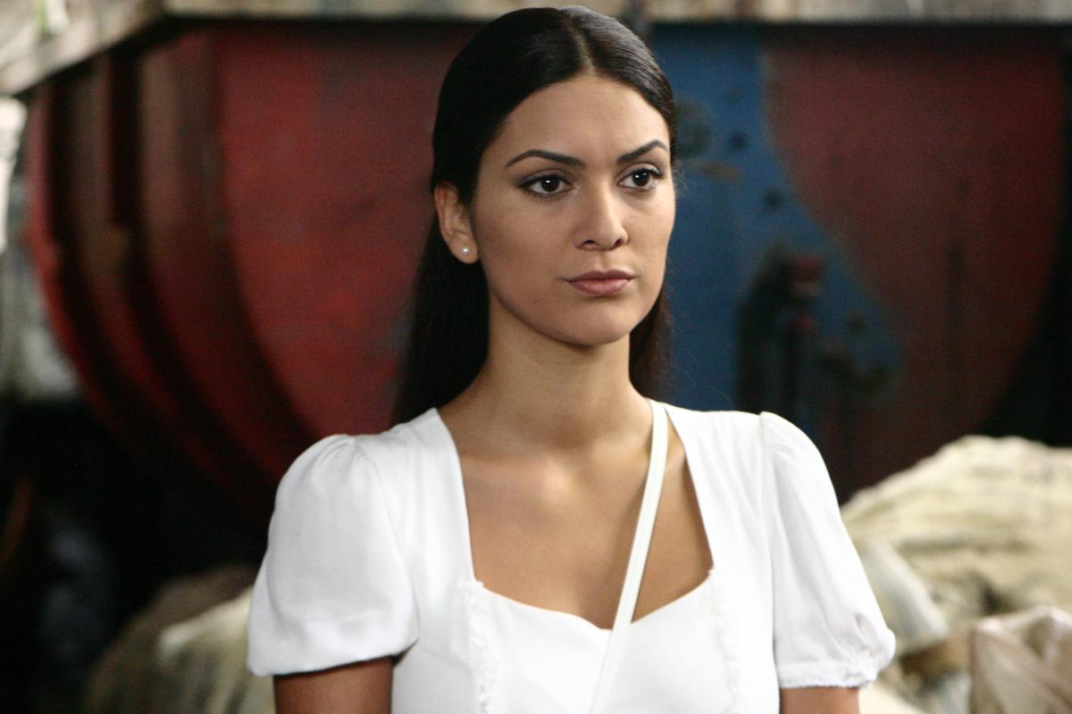 Bergüzar Korel poartă o rochie albă, are părul prins la spate și o figură serioasă