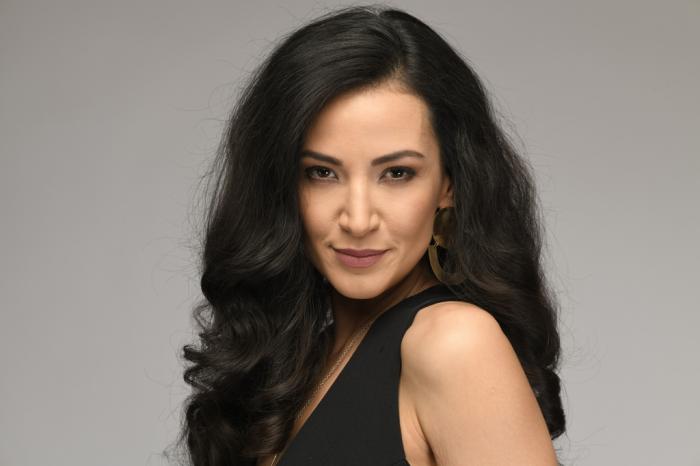 Cemre Melis Çınar poartă o rochie fără mâneci, are părul desprins și zâmbește