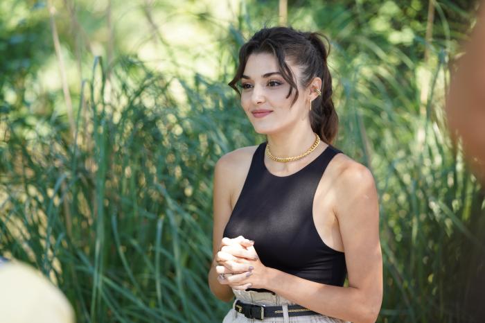 Hande Erçel își ține mâinile împreunate și poartă un maiou negru, dar și părul prins în coadă