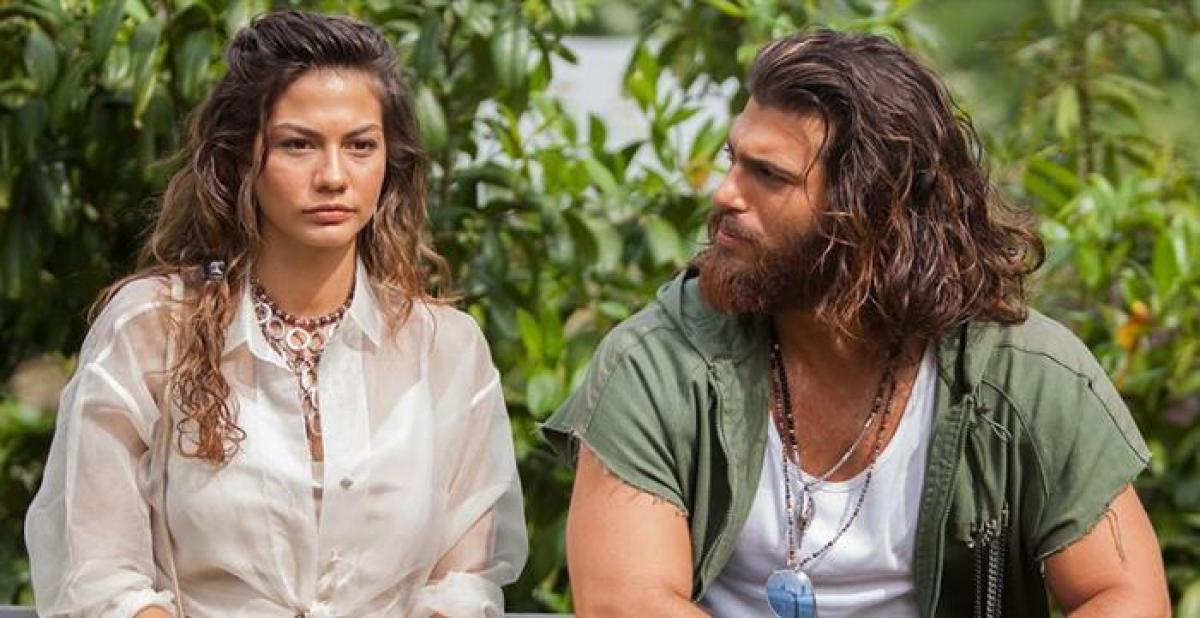 Demet Özdemir și Can Yaman stau unul lângă celălalt. Actorul o privește pe vedetă