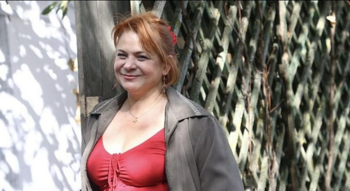 Anca Sigartău poartă o bluză roșie cu decolteu și un hanorac gri