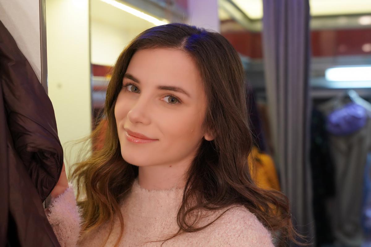 Cansu Tuman poartă o bluză roz pal, are părul desprins și zâmbește