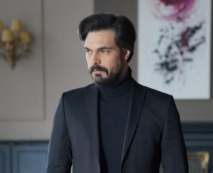 Halil İbrahim Ceyhan poartă o maletă neagră, pe gât și un sacou de aceeași culoare