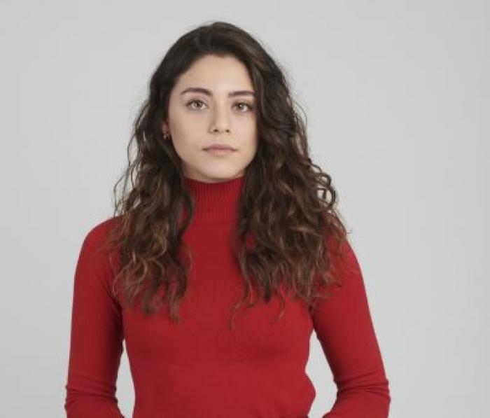 Sıla Türkoğlu poartă o maletă roșie cu mâneci lungi și are părul desprins