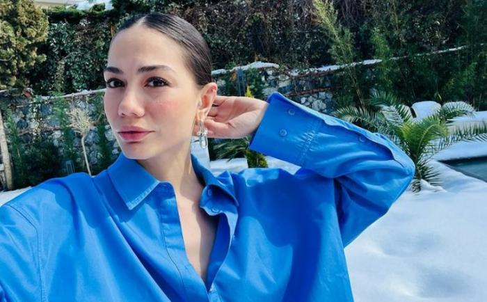 Demet Özdemir poartă o cămașă albastră și are părul prins în coc