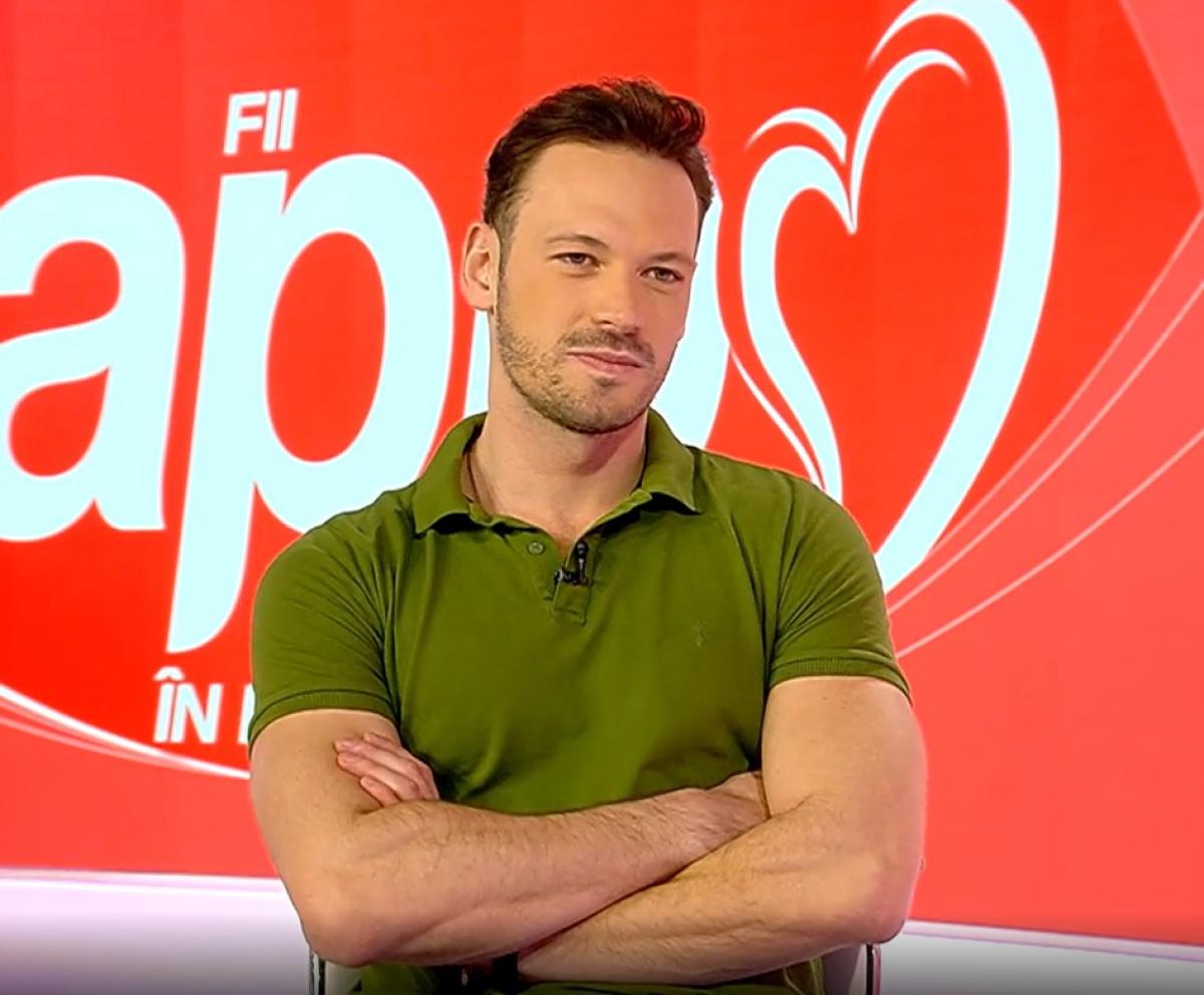 Marius Pancu poartă un tricou verde închis și ține mâinile împreunate