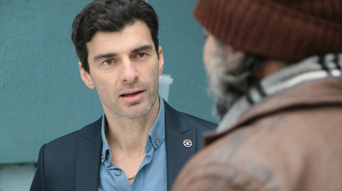 Özgür Özberk poartă o cămașă albastră și sacou închis la culoare