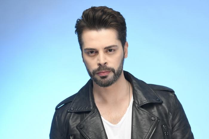 Ali Yasin Özegemen poartă un tricou alb și geacă neagră de piele