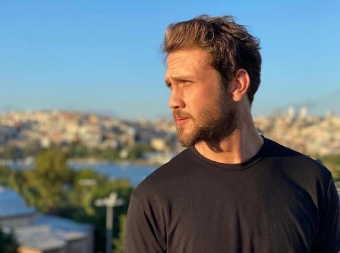Aras Bulut İynemli poartă o bluză închisă la culoare și se uită într-o parte