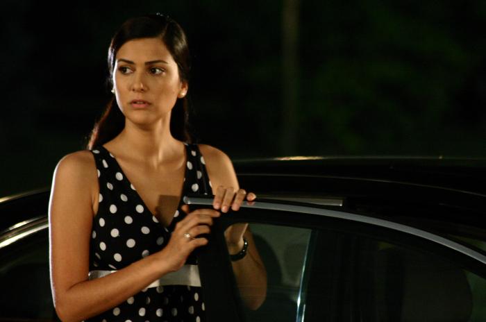 Bergüzar Korel poartă o rochie cu buline și stă cu mâinile pe ușa unei mașini