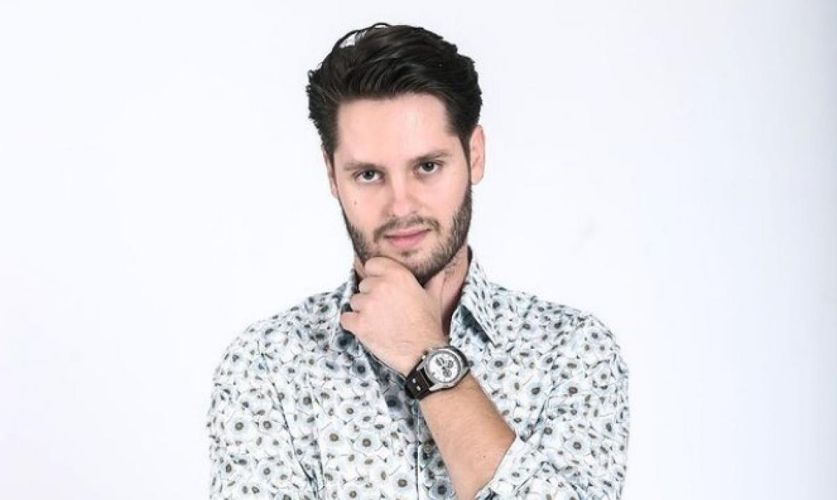 Vlad Vîlciu poartă o cămașă cu flori și își ține mâna stângă la bărbie