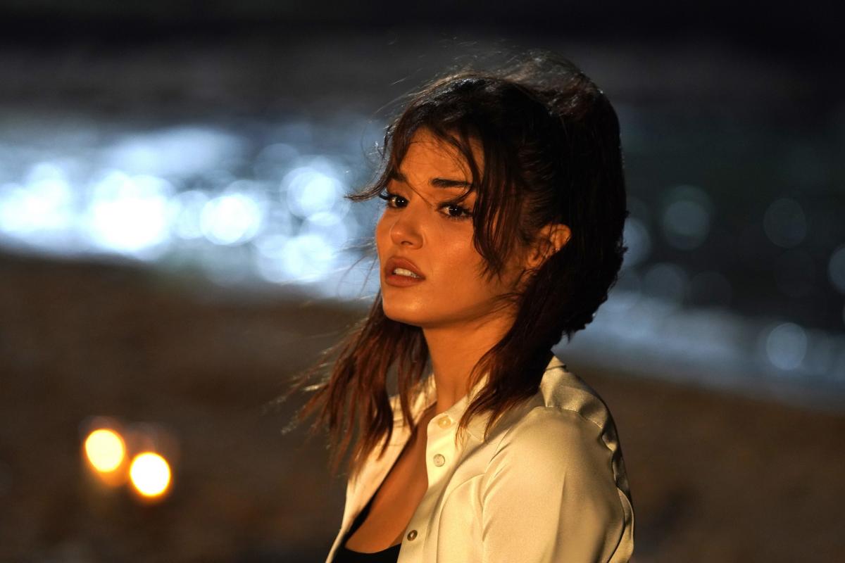 Hande Erçel poartă o cămașă albă și are părul prins în coadă