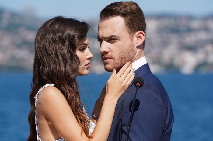 Hande Erçel își ține mâna drepată aproape de fața lui Kerem Bürsin