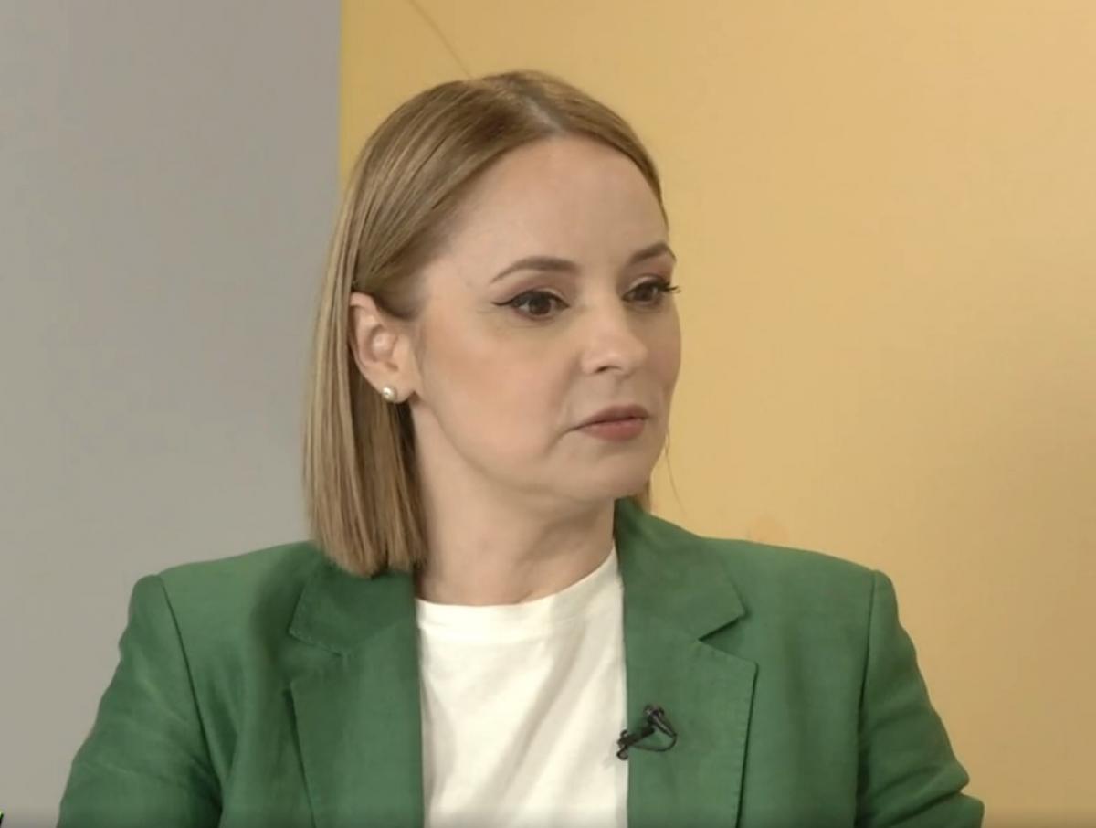 Andreea Marin poartă un tricou alb, sacou verde și are părul scurt