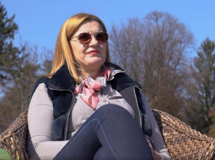 Elisabeta Lipă poartă blugi, bluză cu mânecă lungă, vestă și o eșarfă la gât. Sportiva are părul lung și blond