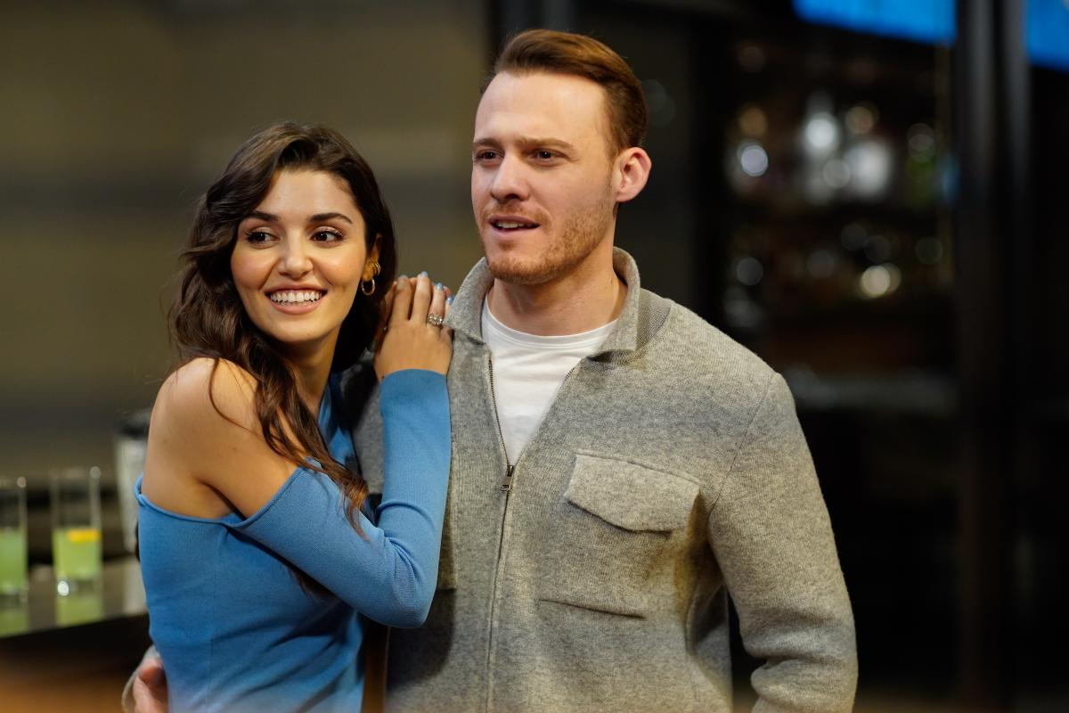 Hande Erçel poartă o rochie albastră și stă cu mâinile pe umărul drept al lui Kerem Bürsin