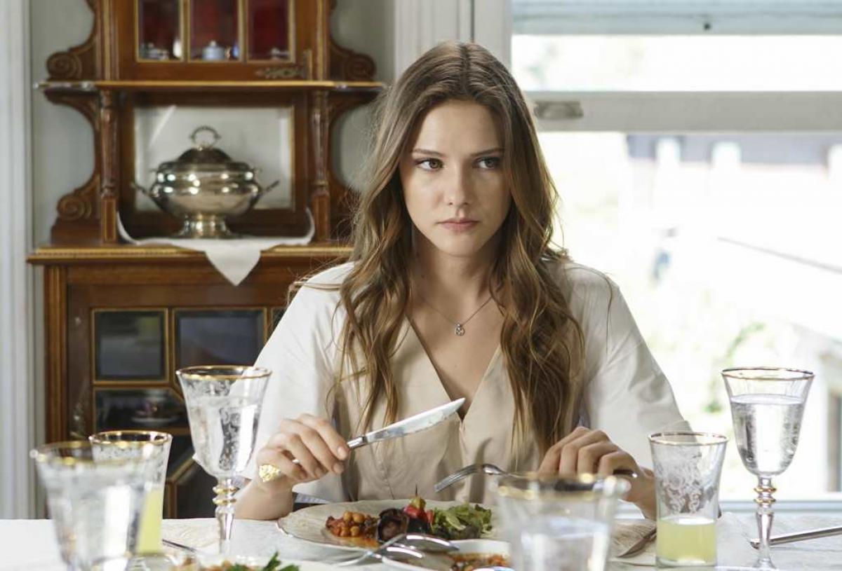 Alina Boz stă la masă cu farfuria de mâncare în față și se uită într-o parte