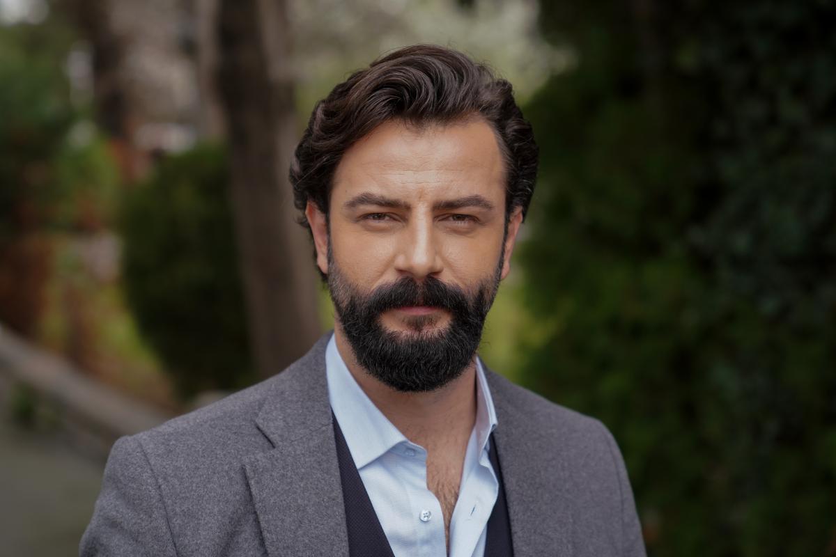 Gökberk Demirci poartă o cămașă albastră și un sacou gri