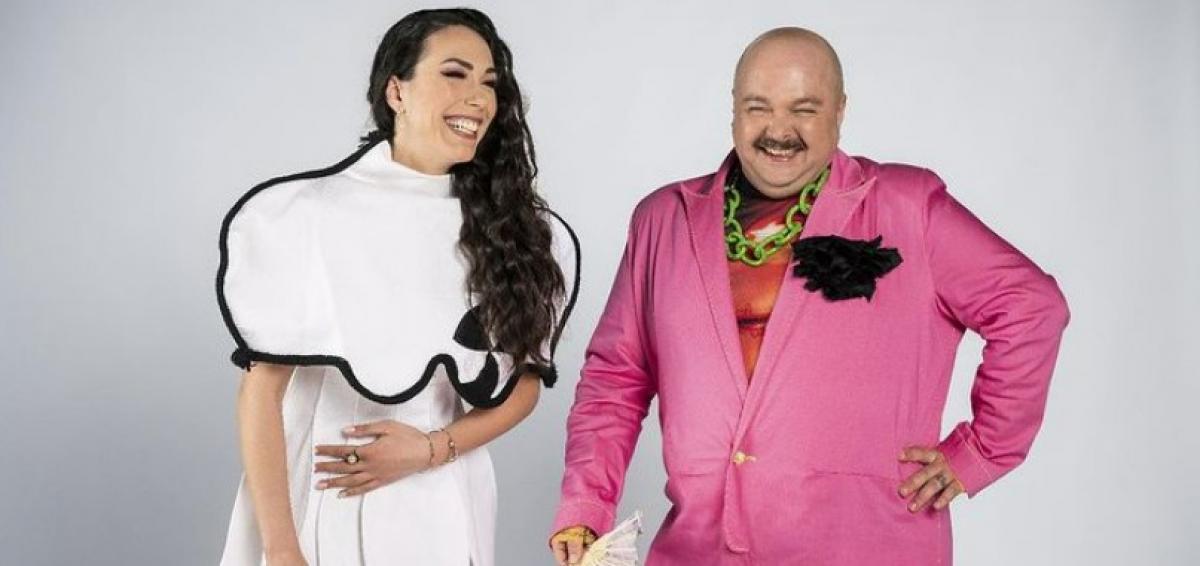 Jazzy Jo poartă un costum alb, zâmbește și are părul coafat pe partea stângă, iar Zarug poartă un costum roz