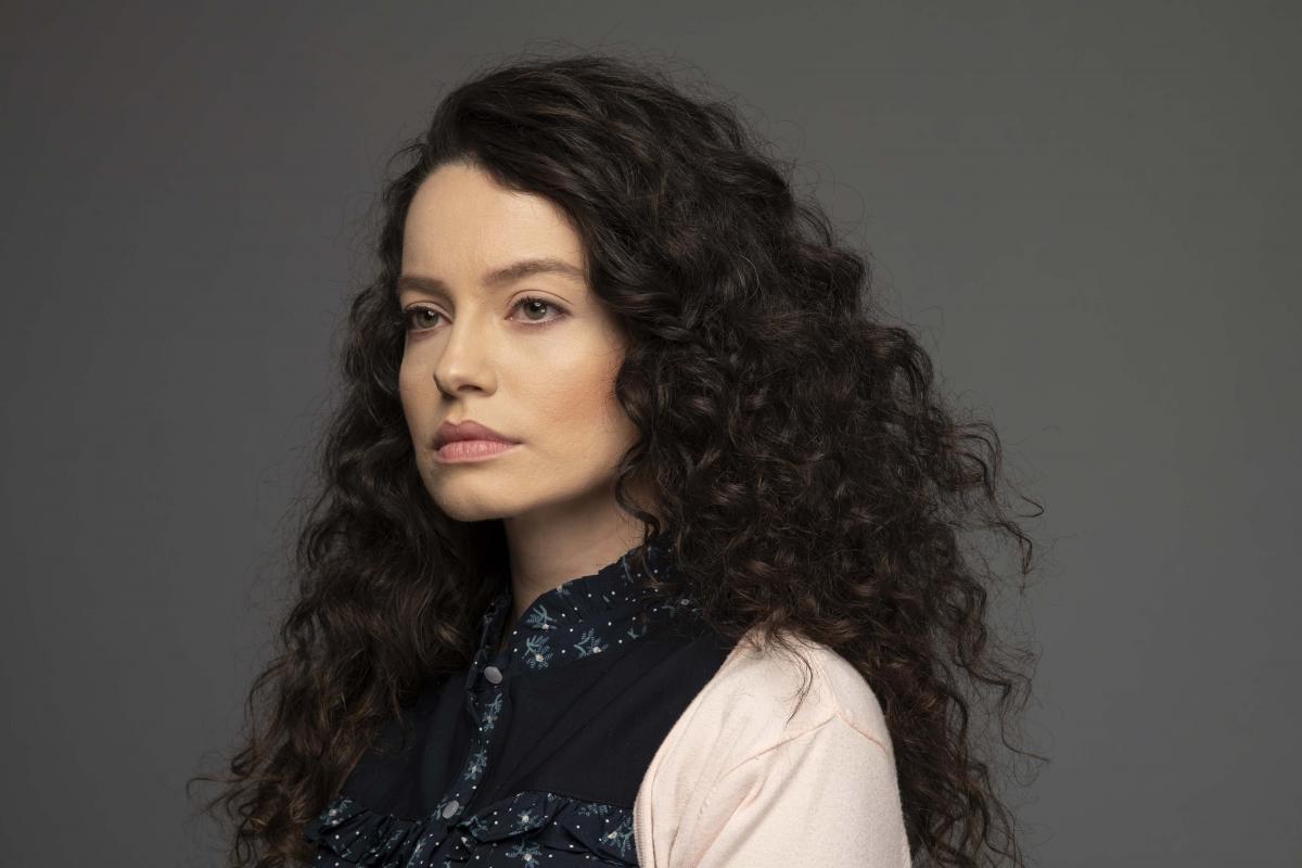 Gizem Arıkan poartă o bluză cu mâneci lungi și o vestă închisă la culoare