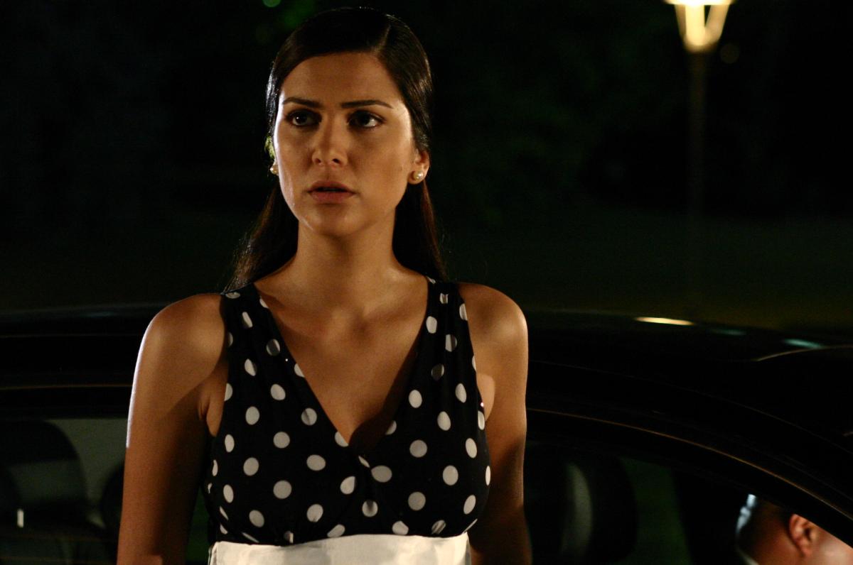 Bergüzar Korel poartă o rochie neagră cu buline albe și are părul coafat pe spate