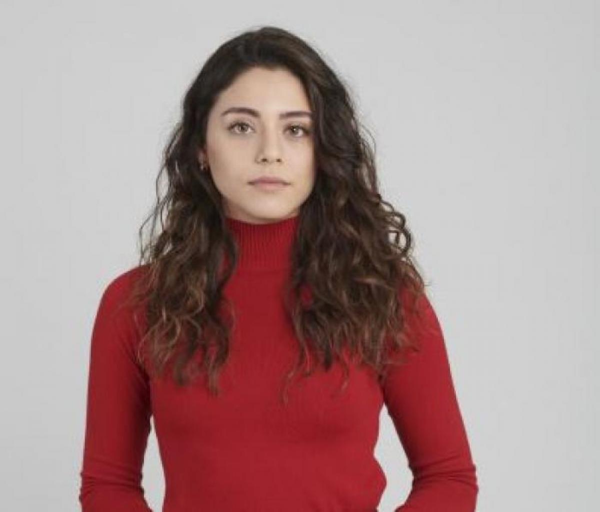 Sıla Türkoğlu poartă o maletă roșie cu mâneci lungi și are părul desprins