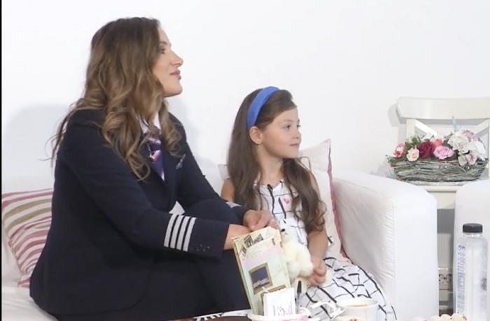 Andreea Lițescu stă pe canapea alături de fetița Sara