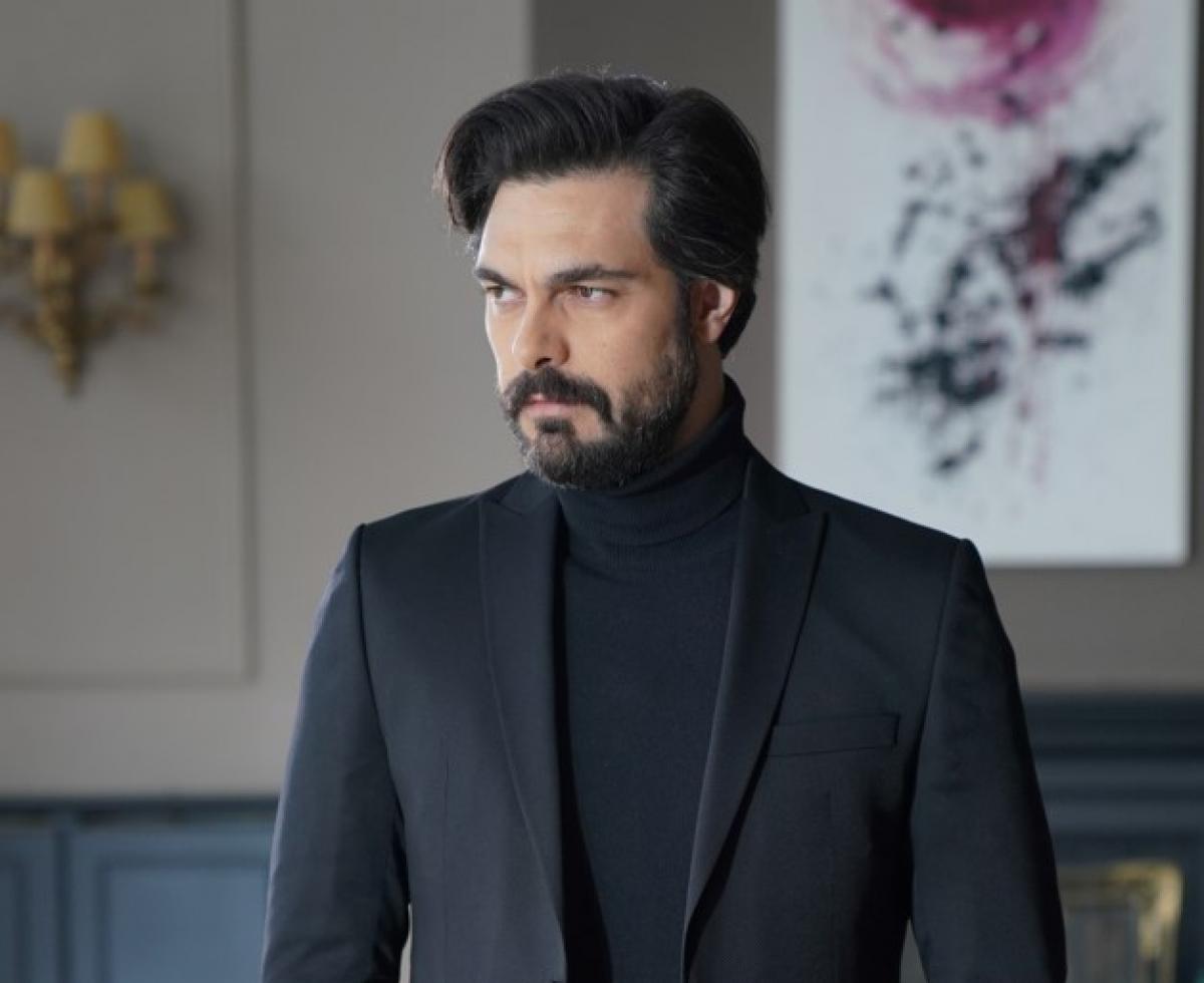 Halil İbrahim Ceyhan poartă o maletă neagră, un sacou de aceeași culoare și privește în depărtare