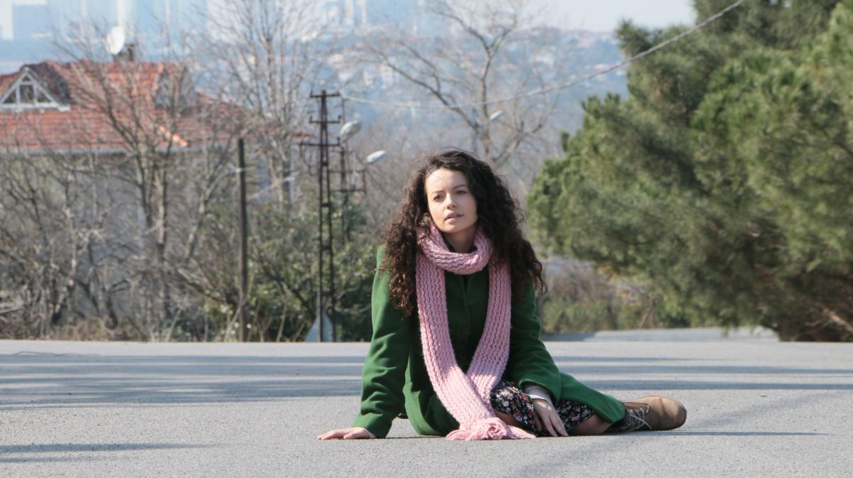 Gizem Arıkan poartă o rochie cu flori, palton verde și un fular la gât