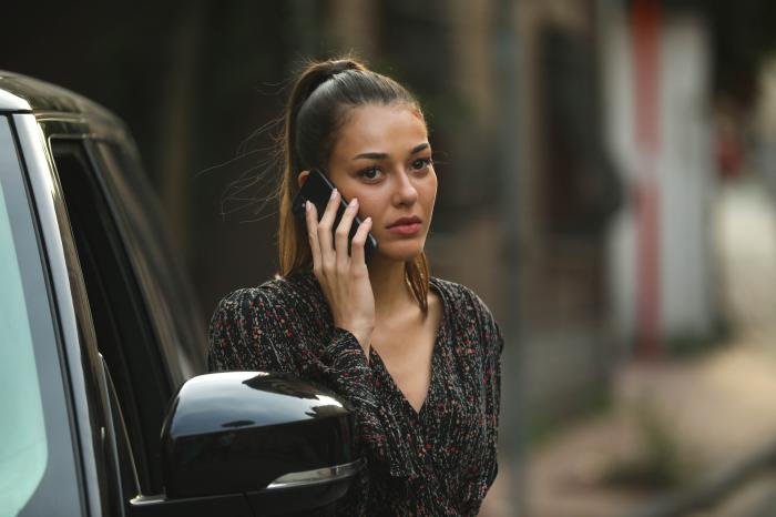 Dilan Çiçek Deniz poartă o rochie închisă la culoare și are părul prins în coadă de cal și vorbește la telefon