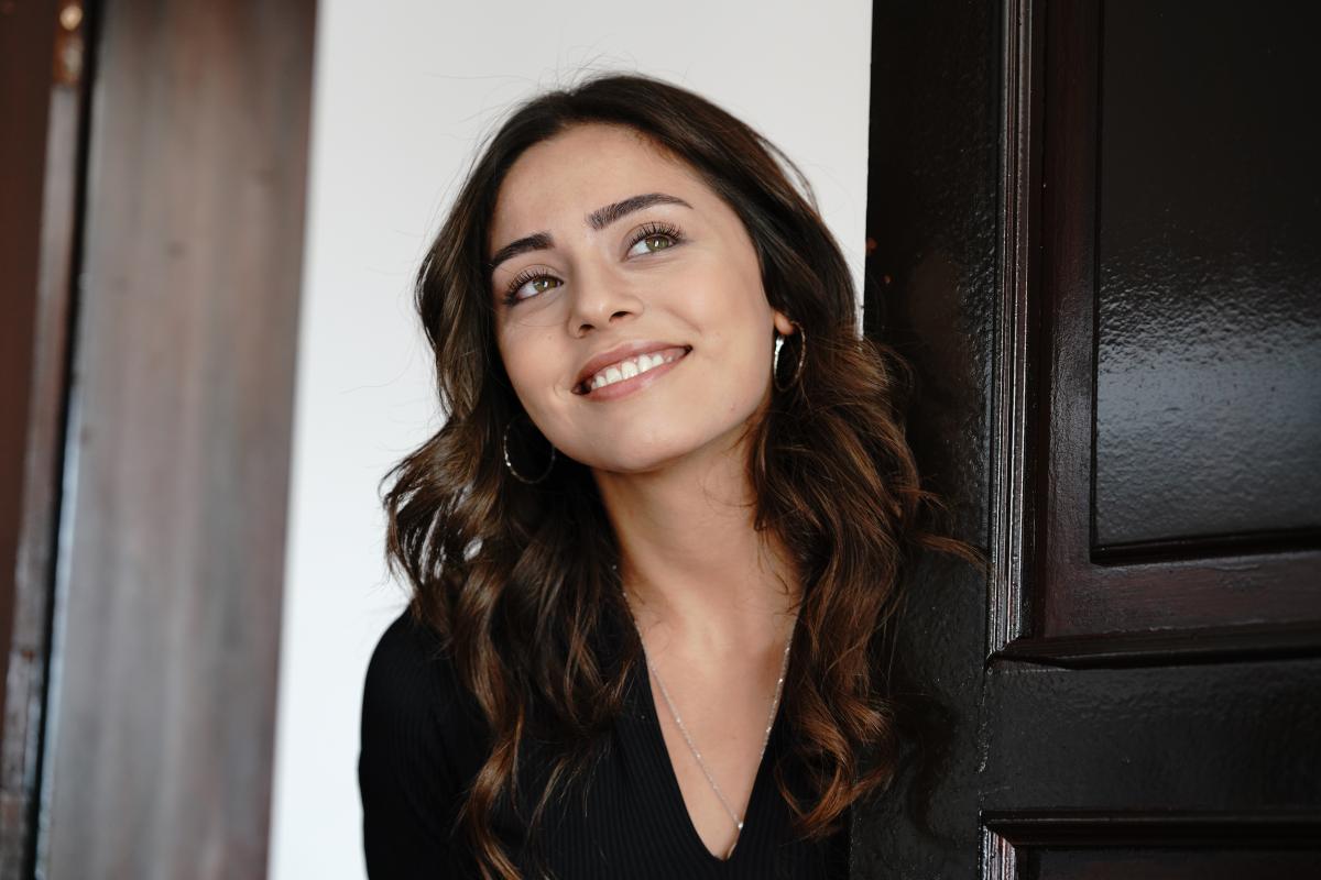 Sıla Türkoğlu poartă o rochie neagră cu mâneci lungi, are părul desprins și zâmbește