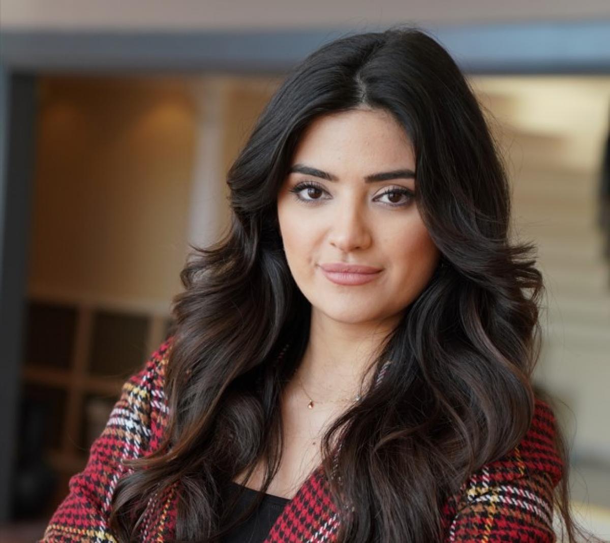 Hilal Yıldız poartă o bluză cu mâneci lungi și are părul desprins, aranjat în față