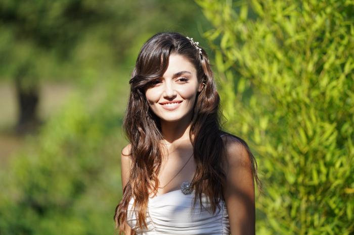 Hande Erçel poartă o rochie albă și zâmbește