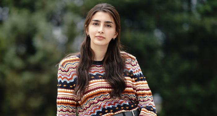 İpek Arkan poartă pantaloni negri și un pulover cu imprimeu