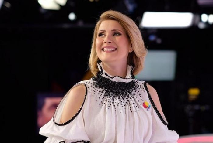 Alessandra Stoicescu poartă o bluză alb-negru și zâmbește