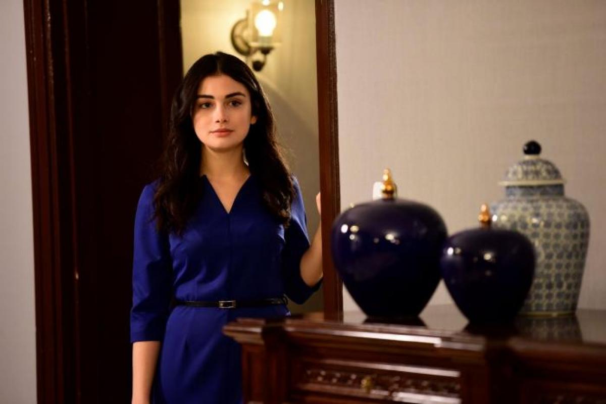 Özge Yağız poartă o cămașă închisă la culoare și are părul desprins