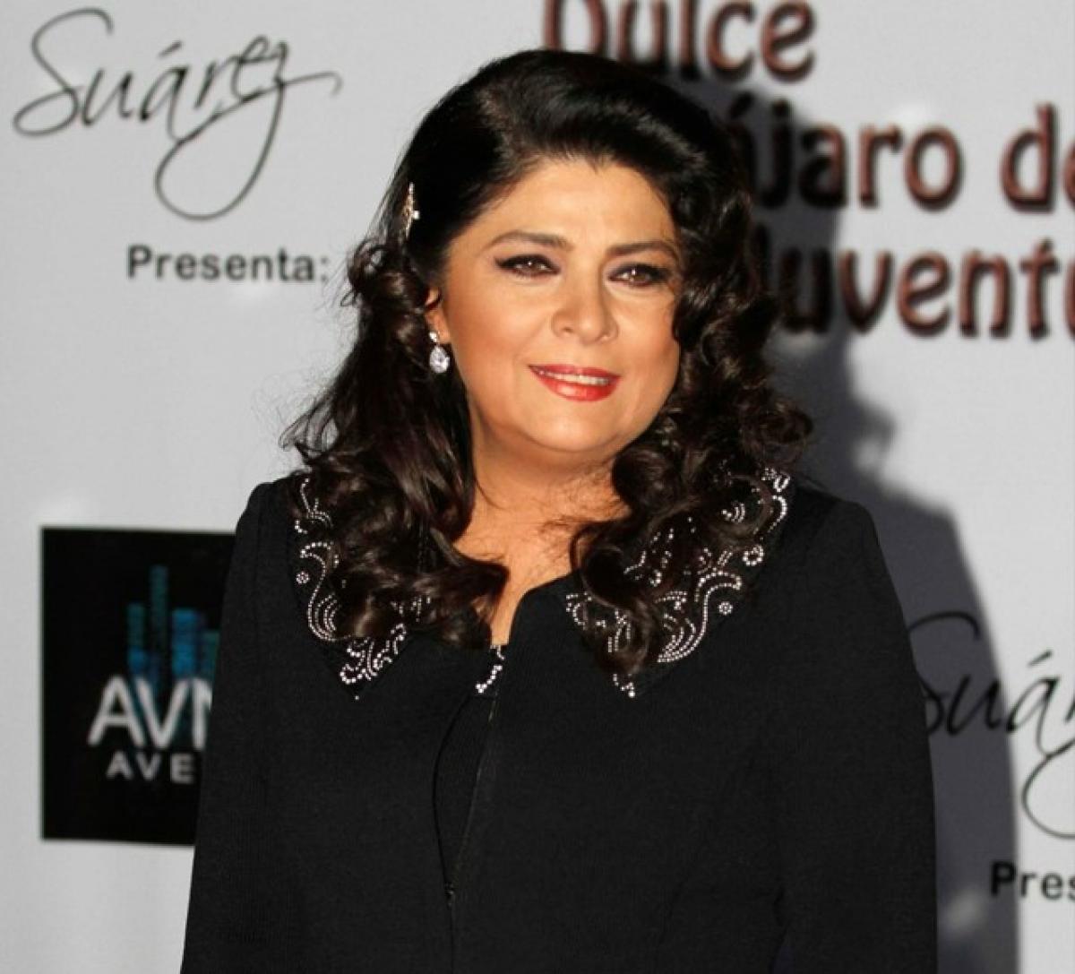 Victoria Ruffo poartă un costum negru, are părul desprins și ondulat și zâmbește
